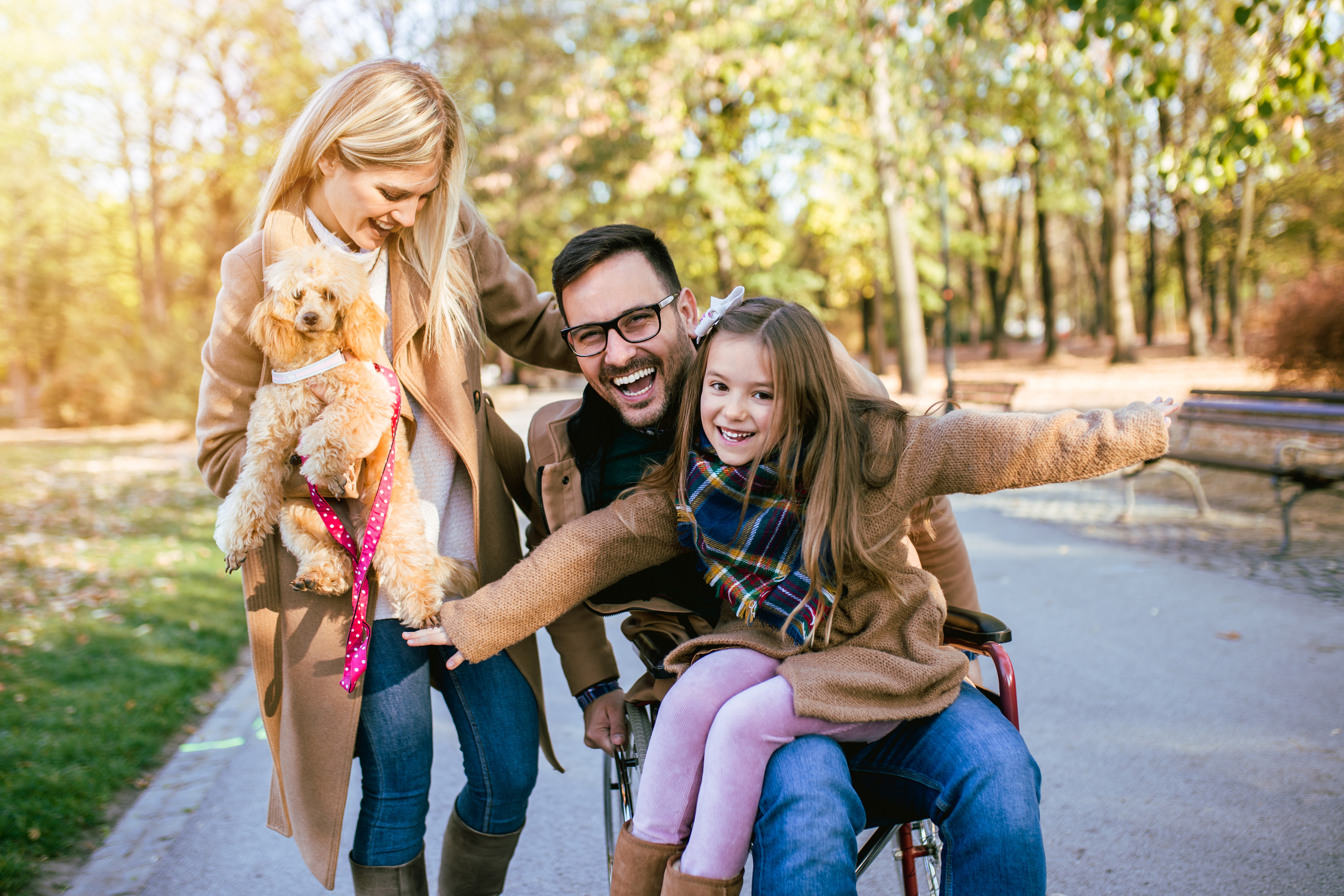 Family with wheelchair user, child, and dog enjoying a park